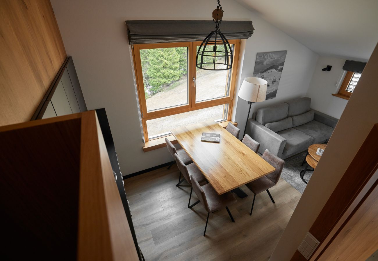 Woonkamer met bank, tafel en keuken in het Bartgeier 119 Alpin-Resort Montafon
