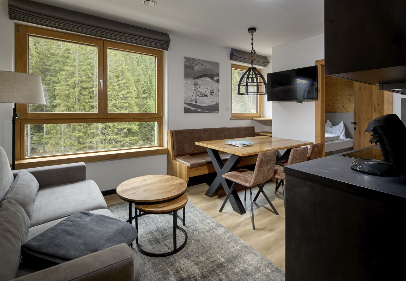 Living area with sofa, table and kitchen in the Wanderfalke 216 Alpin-Resort Montafon
