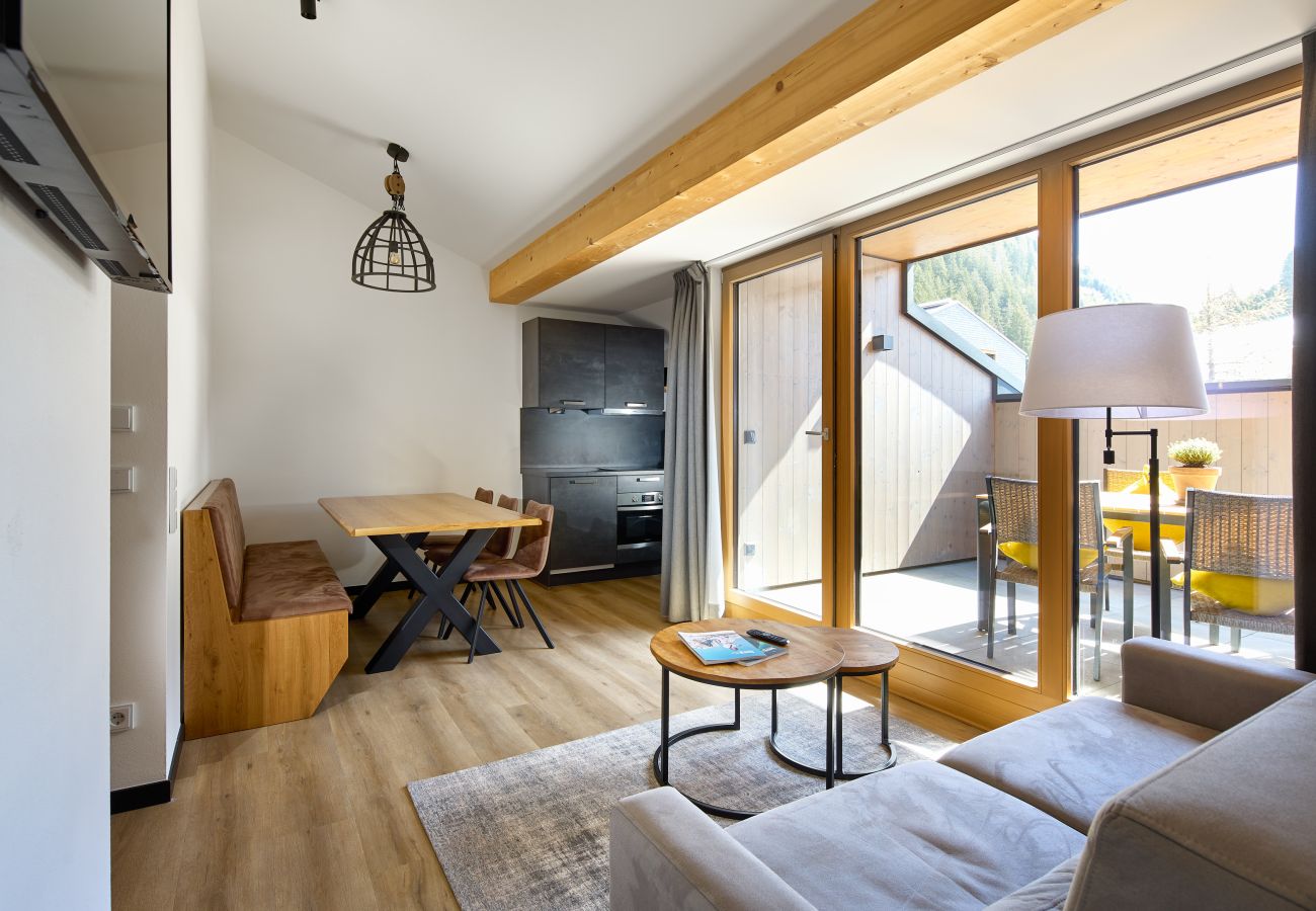 Living area with sofa, table and kitchen in the Mauerläufer 323 Alpin-Resort Montafon