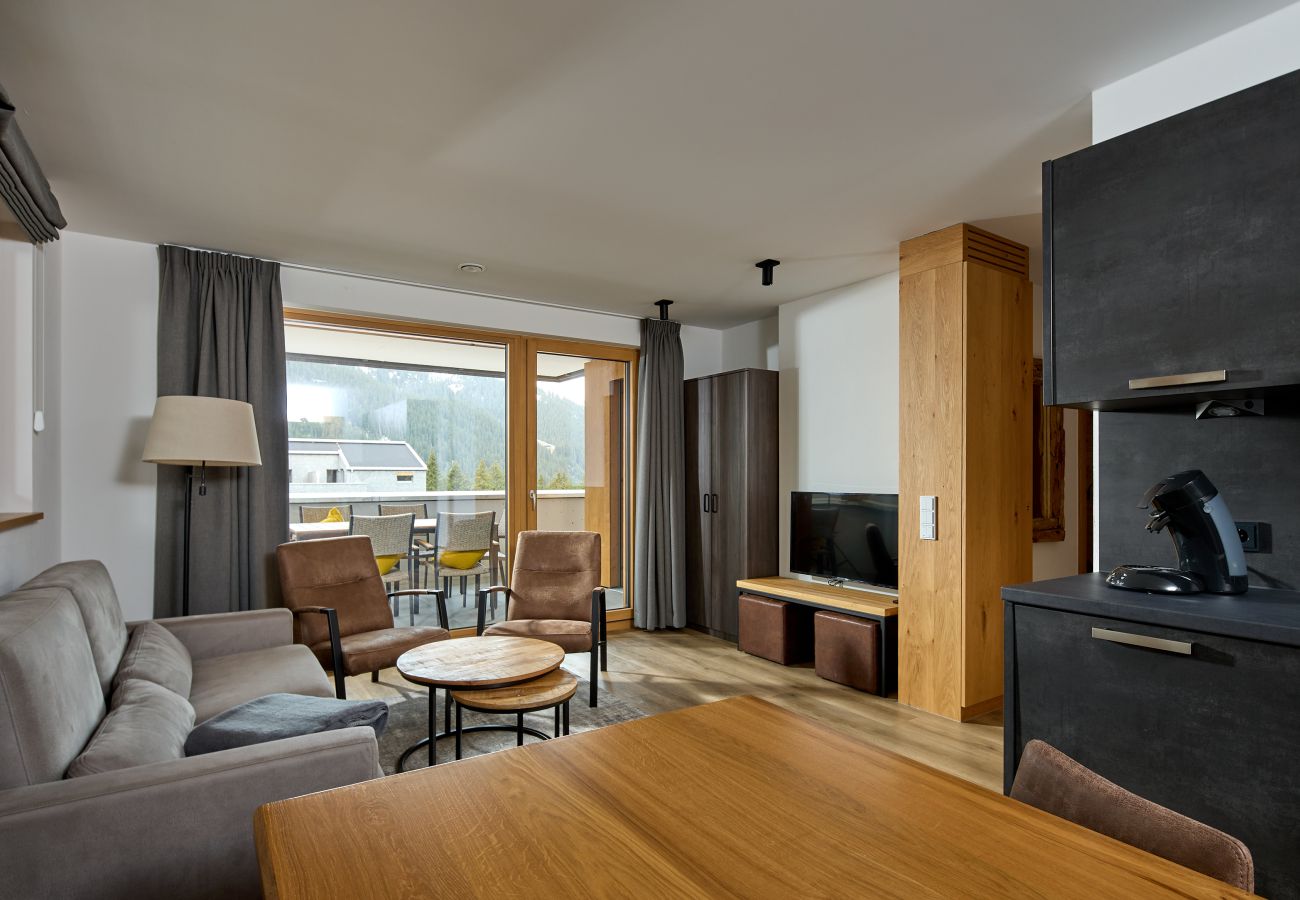 Wohnbereich mit Sofa, Tisch und Küche im Bartgeier 204 Alpin-Resort Montafon
