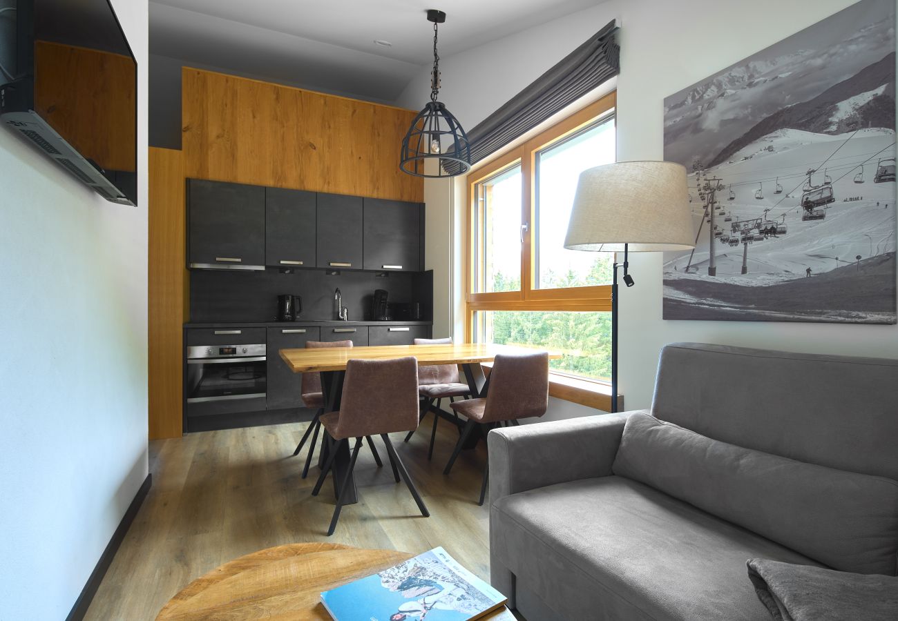 Wohnbereich mit Sofa, Tisch und Küche im Bartgeier 118 Alpin-Resort Montafon